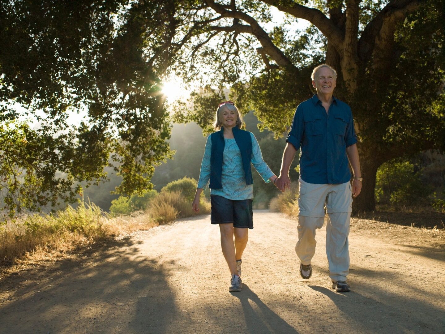 A man and woman holding hands while walking down the road.