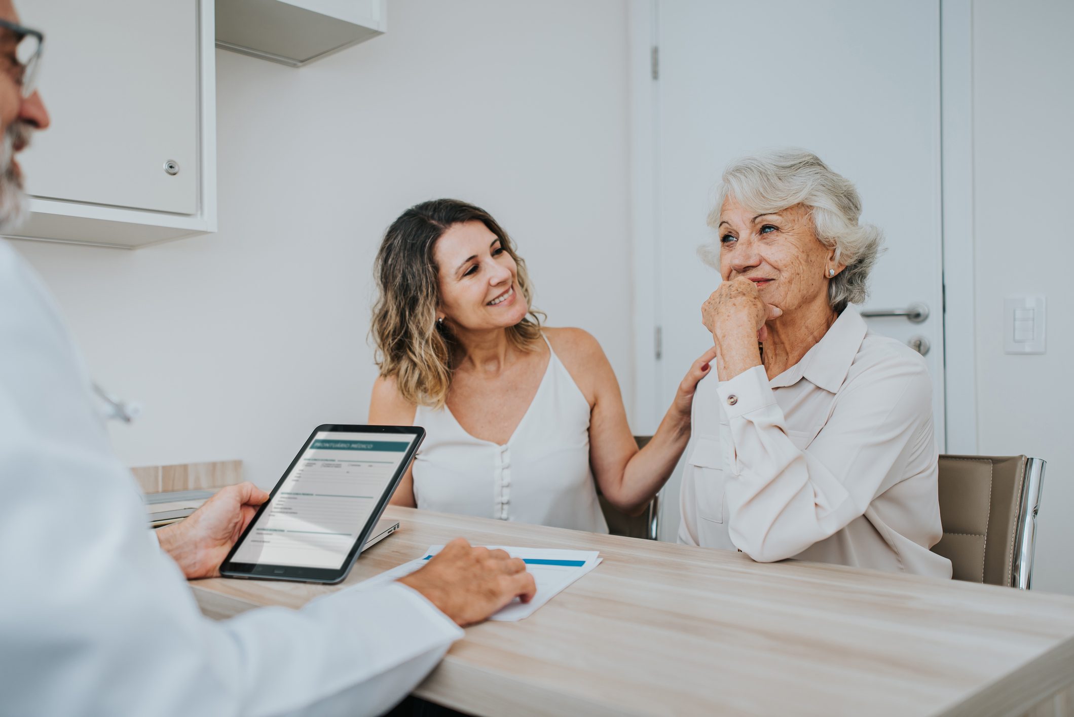 Doctor with older woman and supportive daughter
