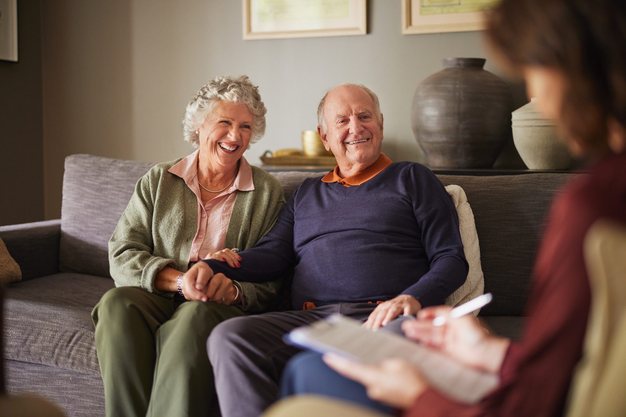 Smiling senior couple holding hands on couch