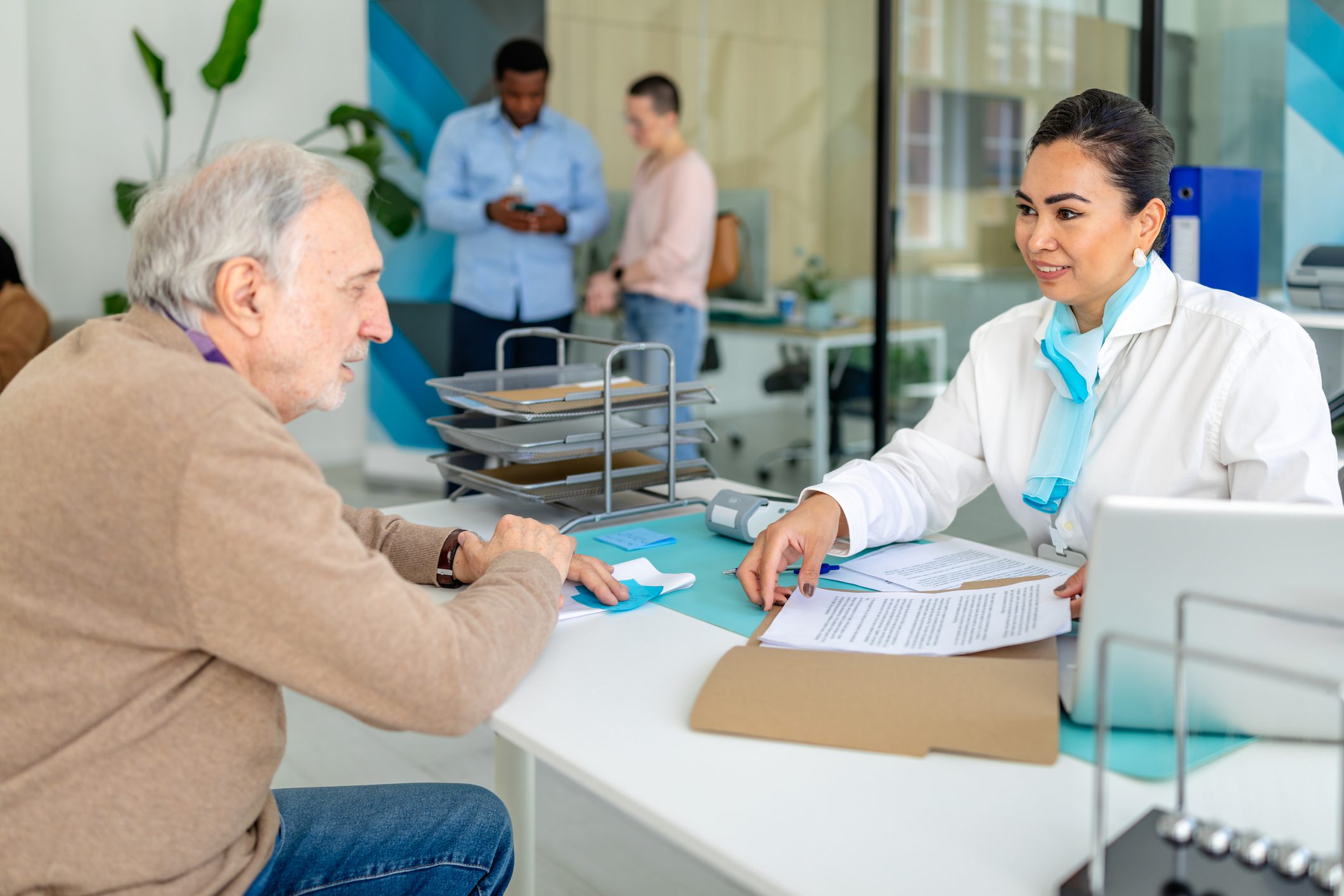 A senior man consults with a staff member during the Annual Enrollment Period at a service center.