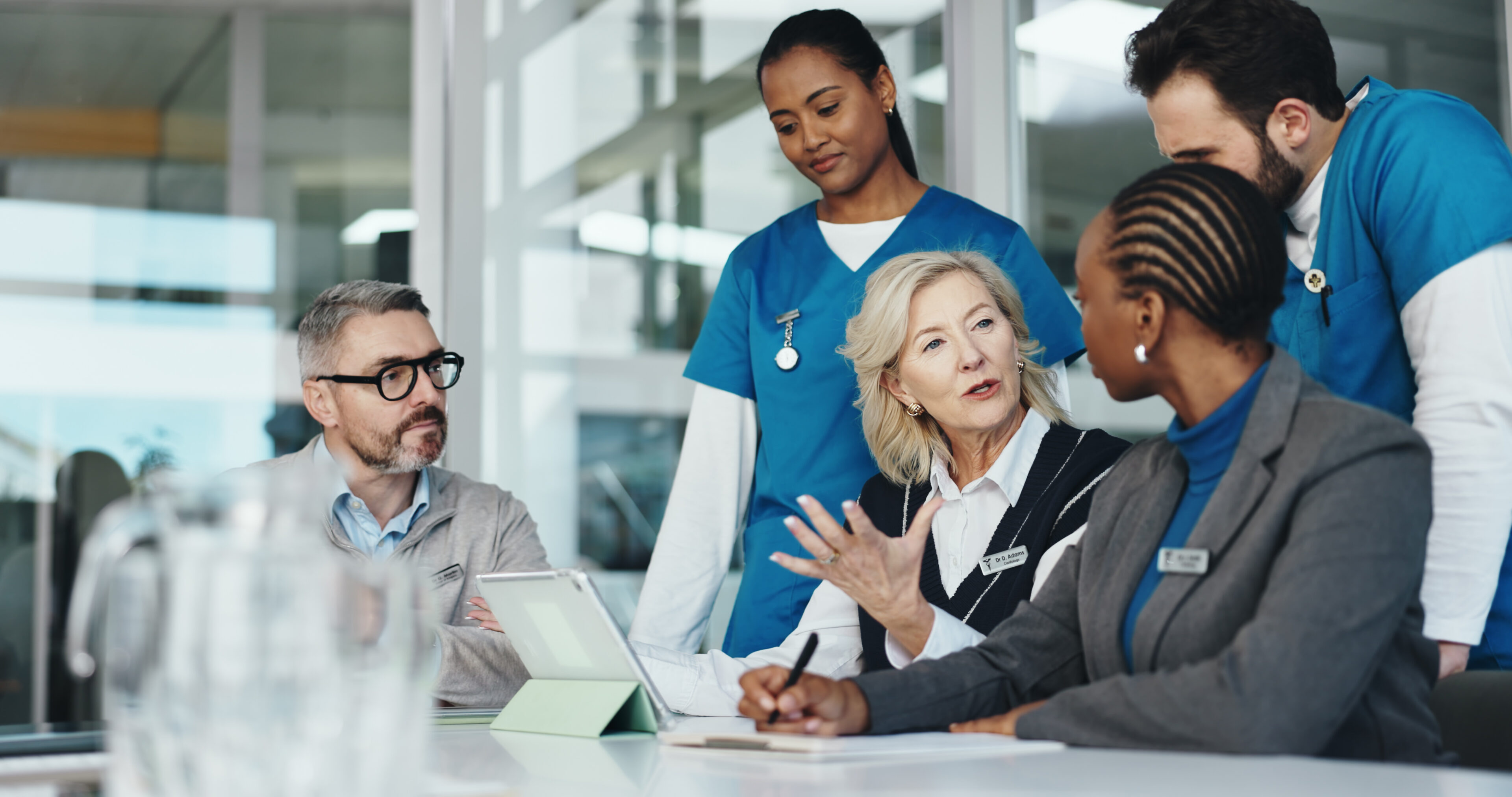 A diverse group of professionals engaged in a collaborative discussion around a table, focusing on work-related topics.