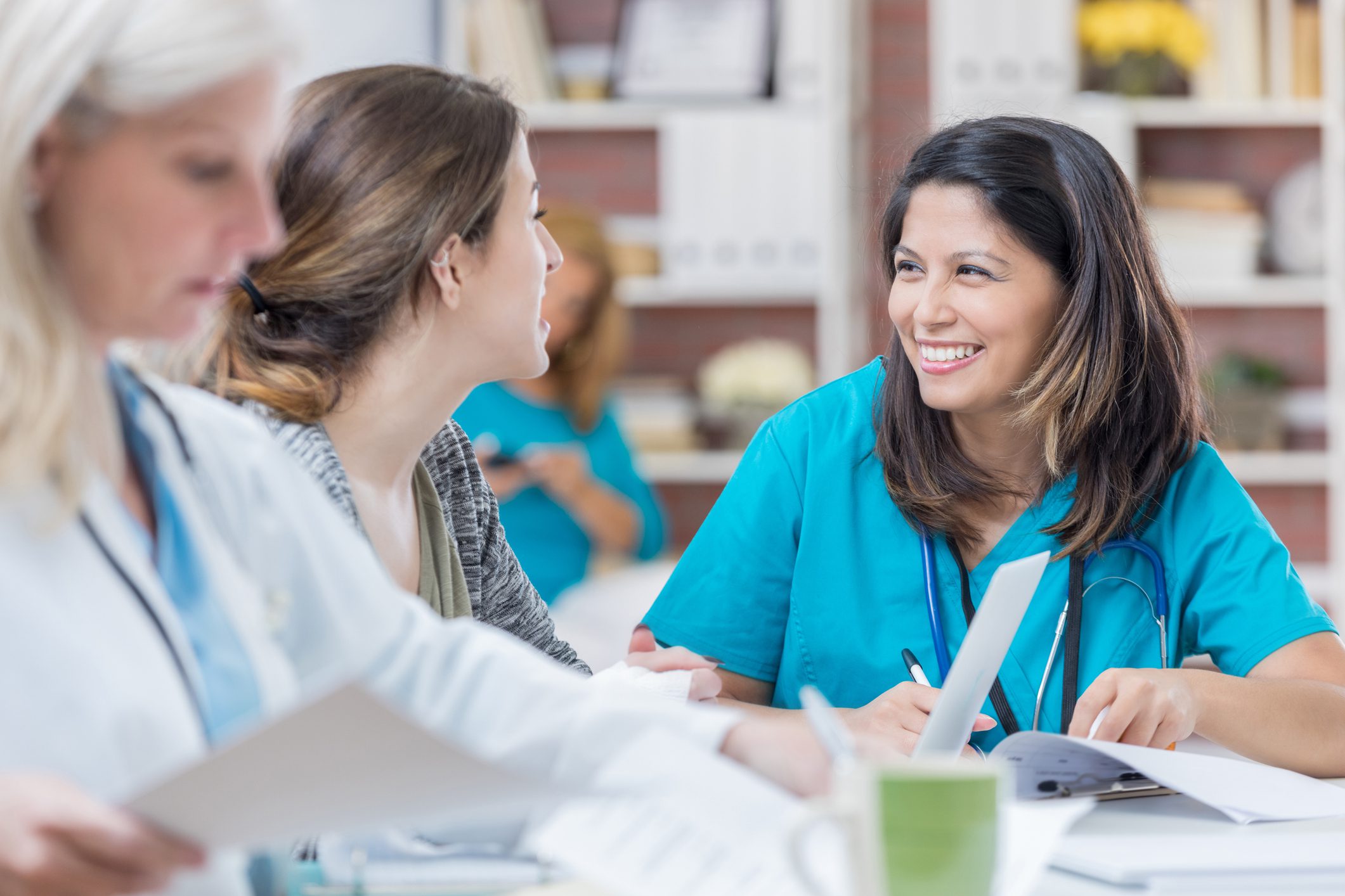 Healthcare professionals engage in a collaborative discussion, sharing documents and ideas in a bright, inviting setting.