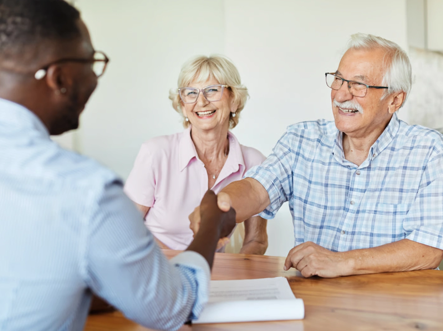 A Medicare advisor shakes hands with a senior couple, discussing Medicare Advantage Plans in a welcoming setting.