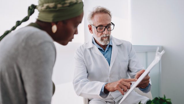 Doctor consulting patient, pointing at clipboard