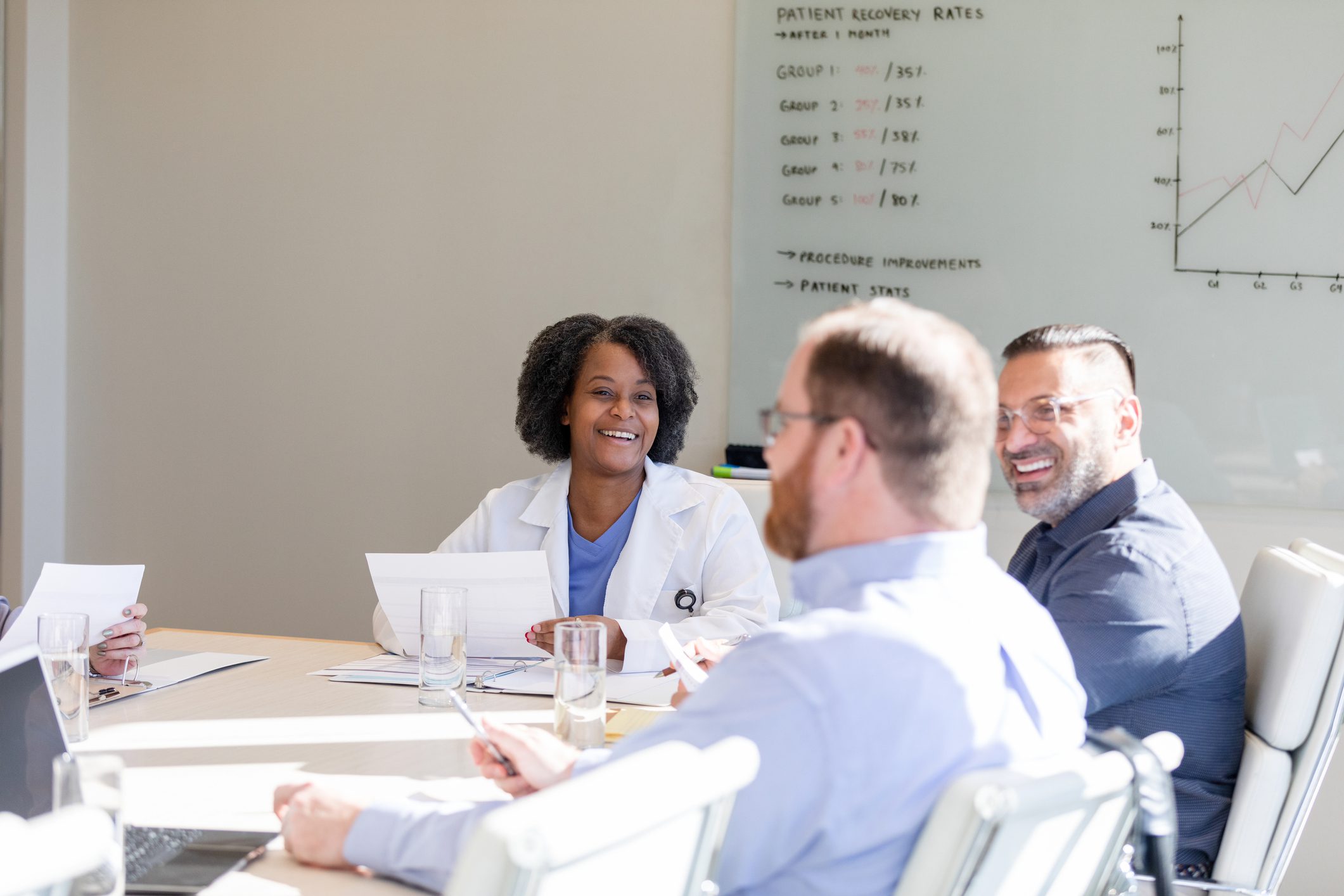Doctors smiling in meeting around conference table