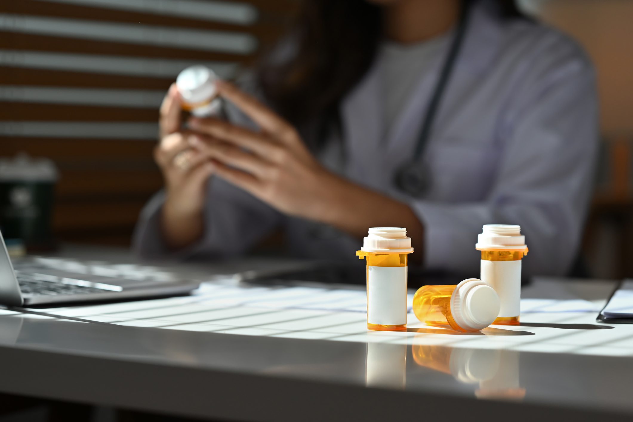 Prescription pill bottles on desk with healthcare professional