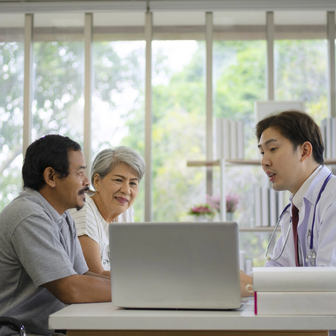 Doctor consulting elderly couple with laptop