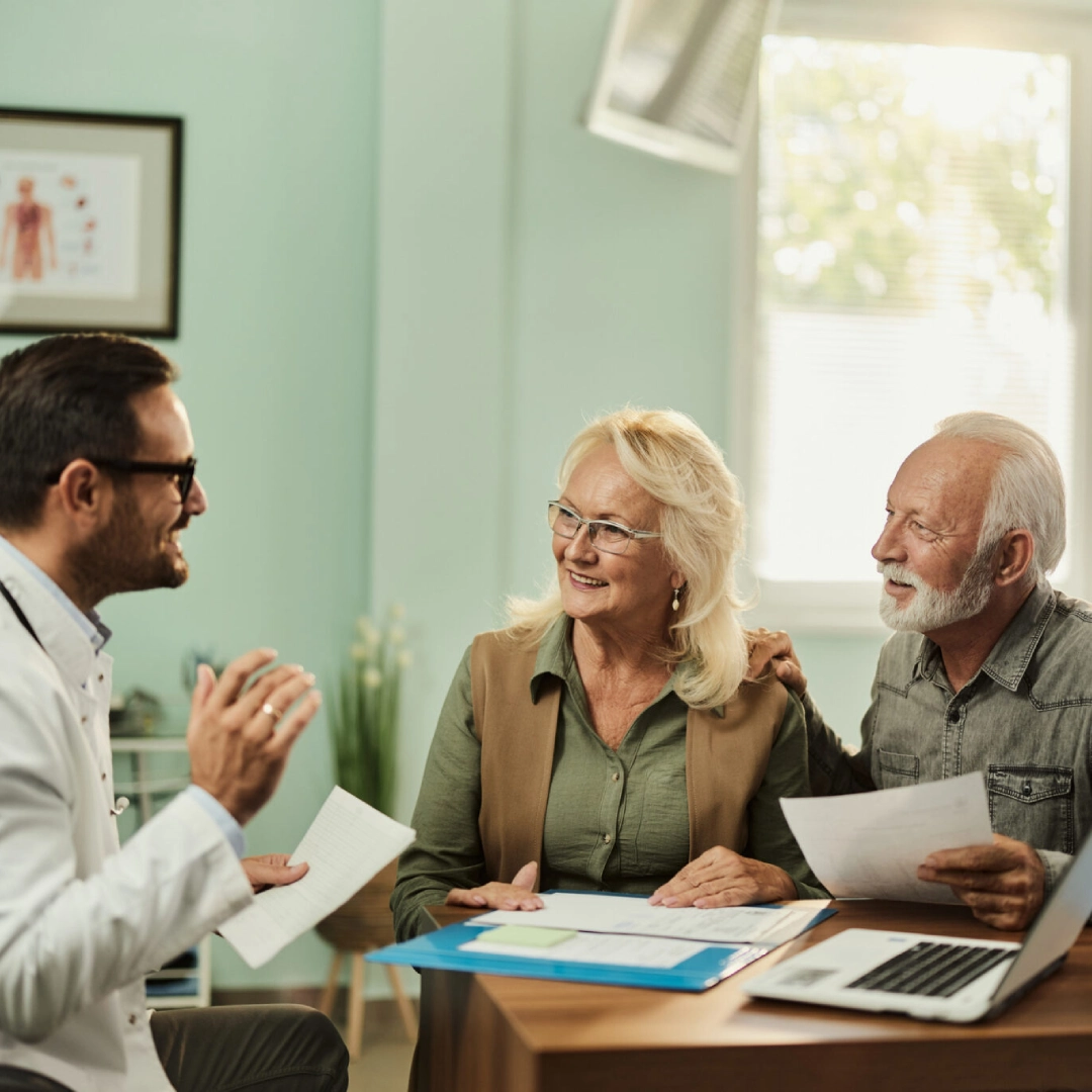 Doctor consulting smiling senior couple in clinic