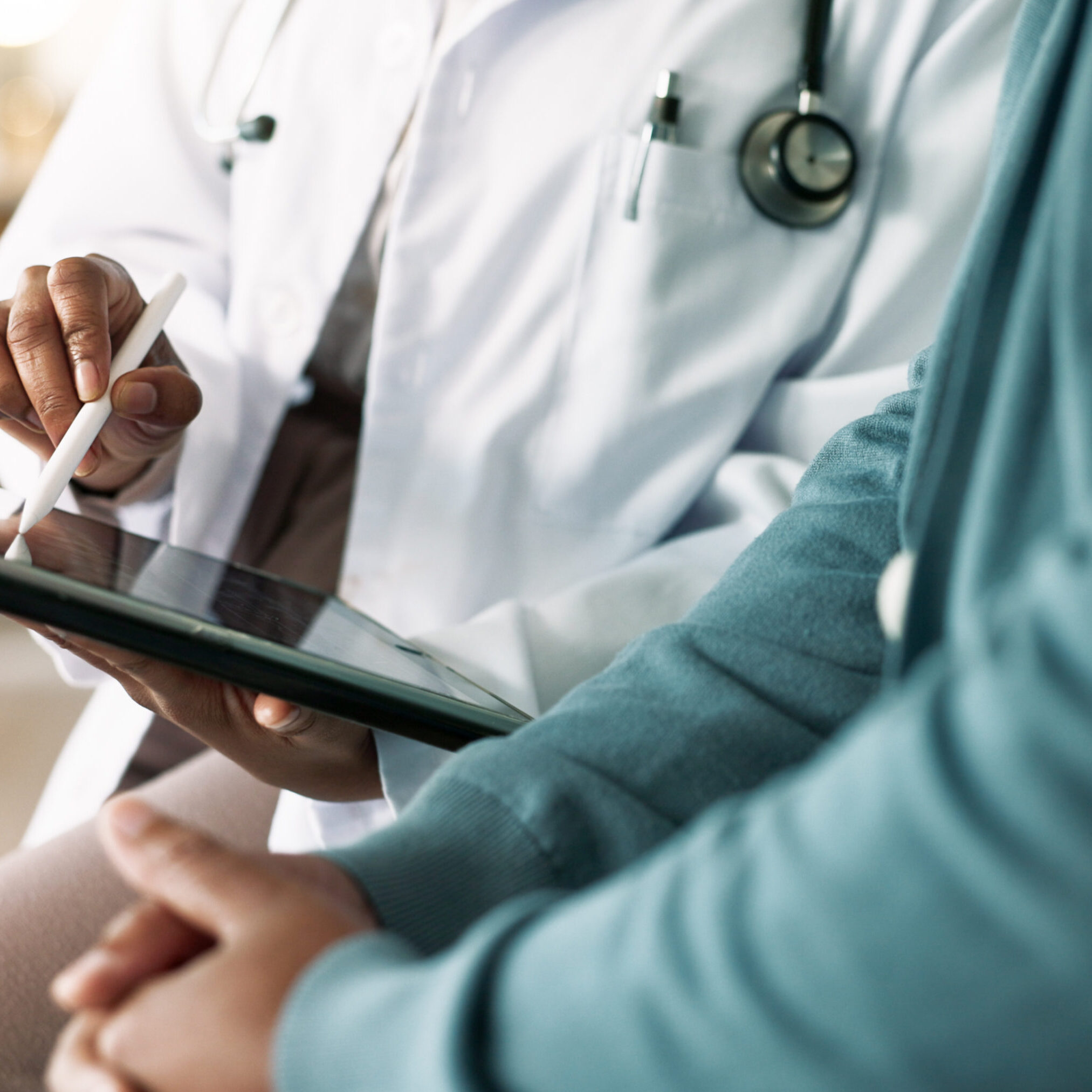 Doctor with stethoscope reviewing tablet with patient