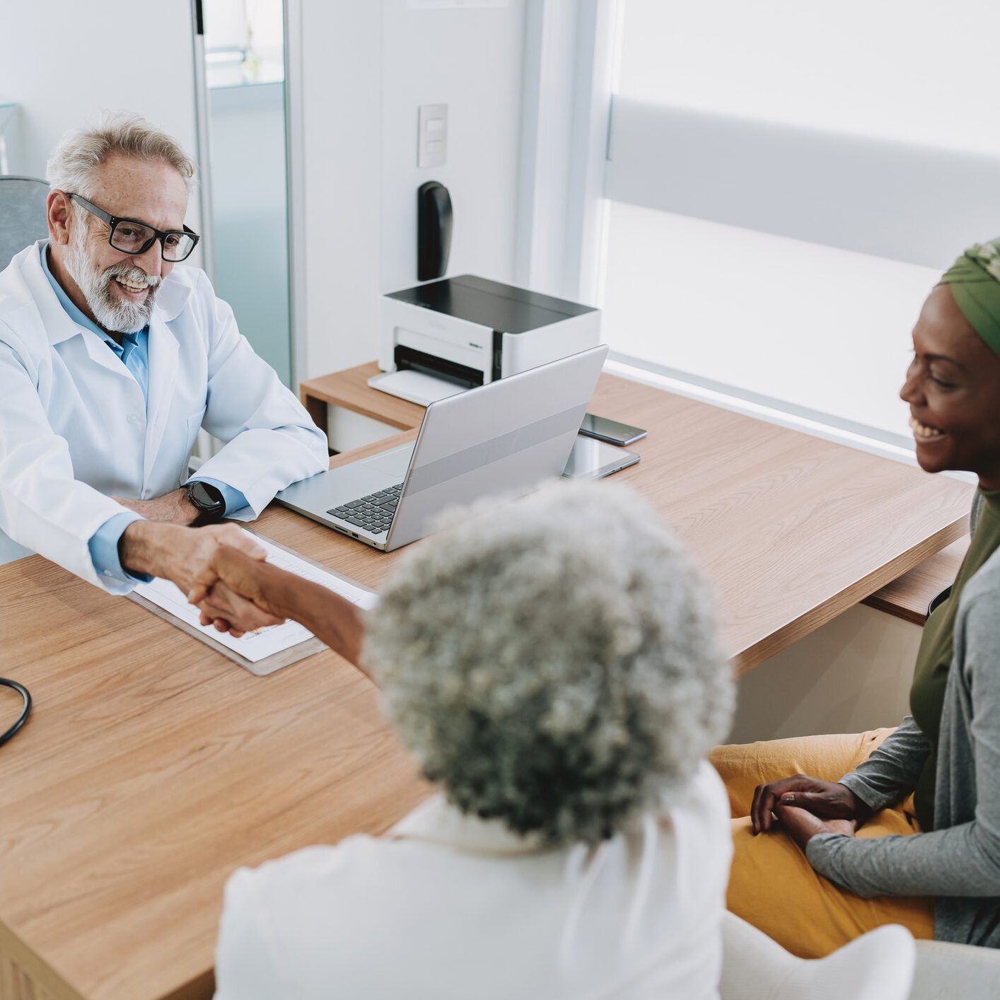 A doctor shakes hands with a patient while discussing Medicare Advantage Plans in a modern office setting.